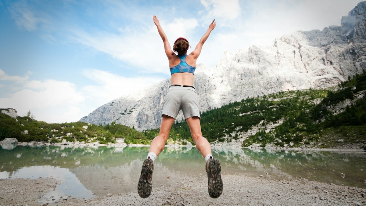 woman jumping wearing blue sports bra and grey shorts